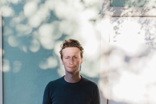 Edgar Kunz standing in front of blue wall